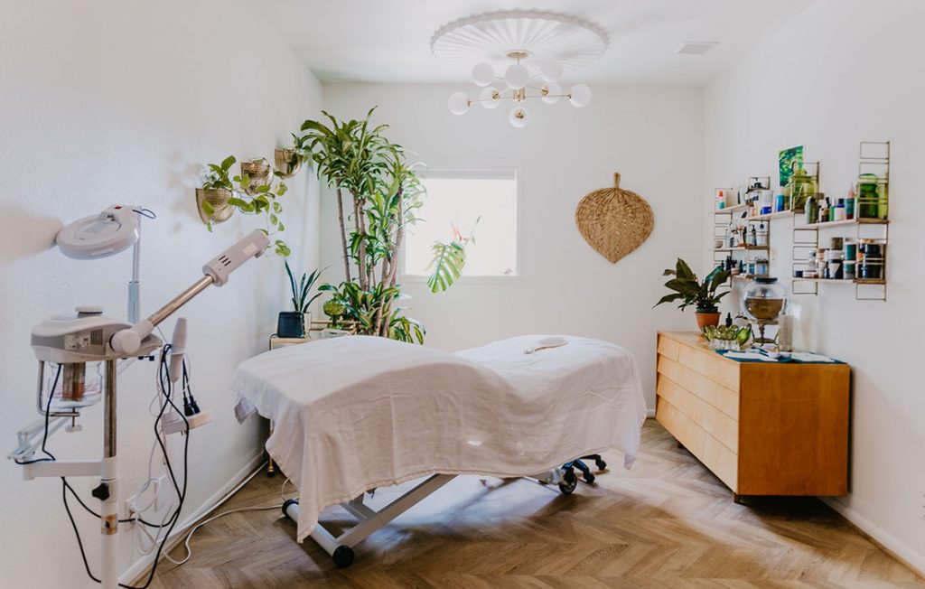 The treatment room at Your Daily Ritual, bright and plant-filled with a linen-draped facial bed